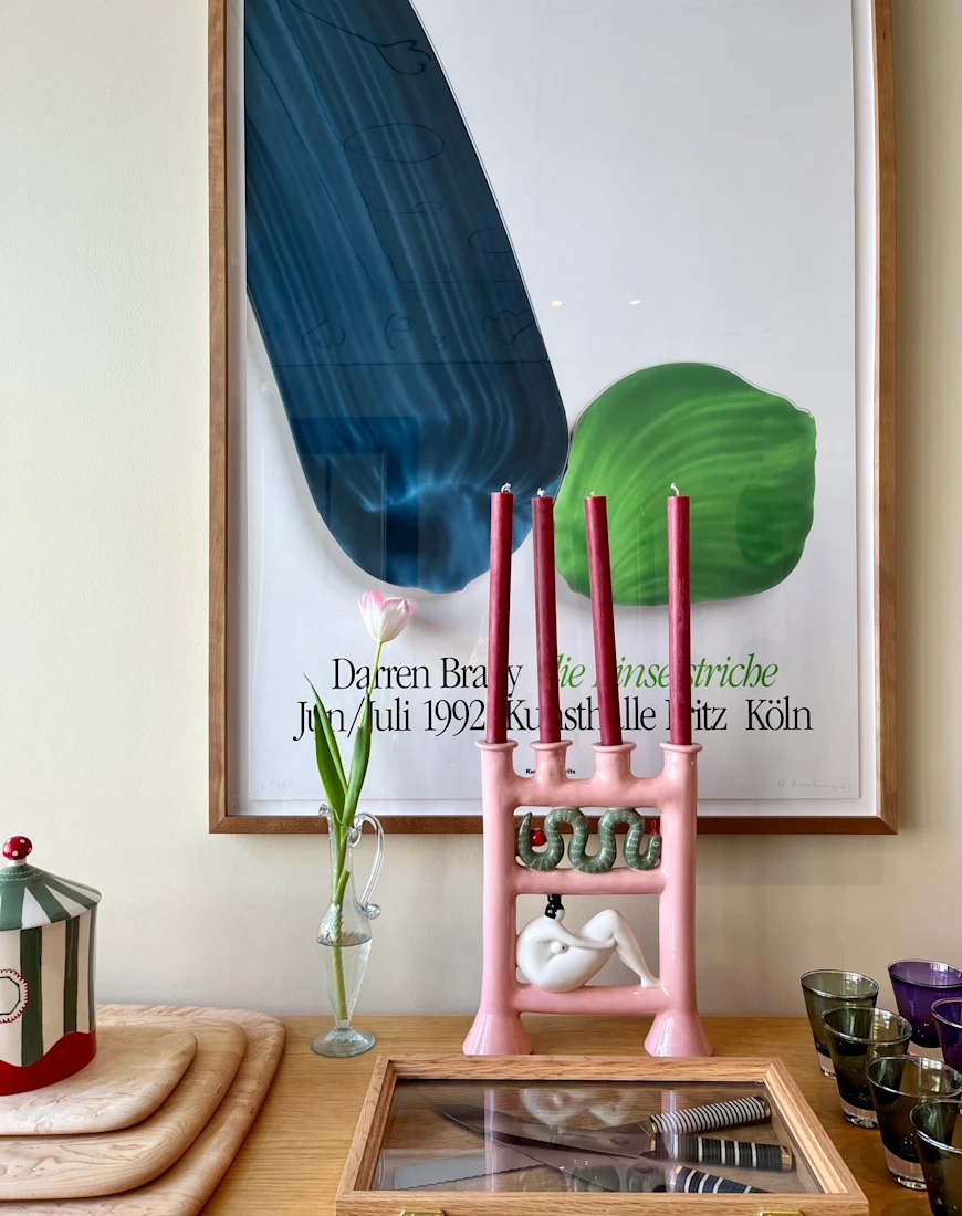 a funky pink candleholder in front of a large painting