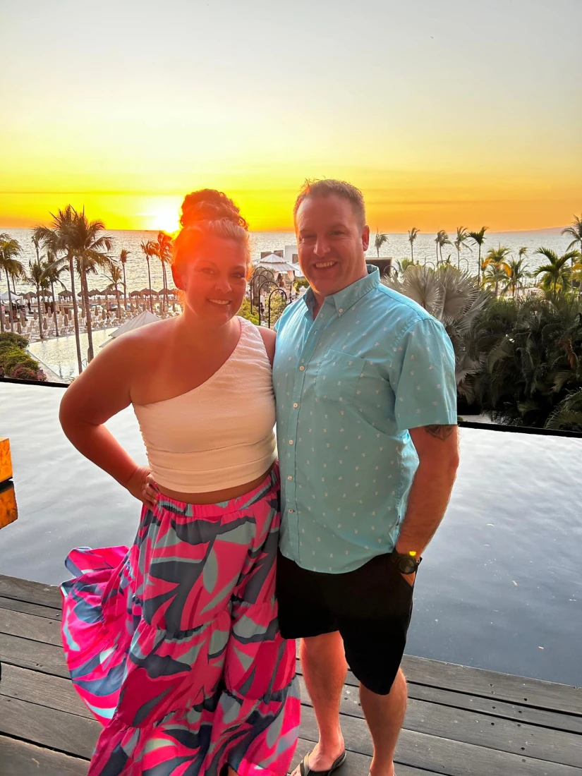 Two people posing for a photo at sunset