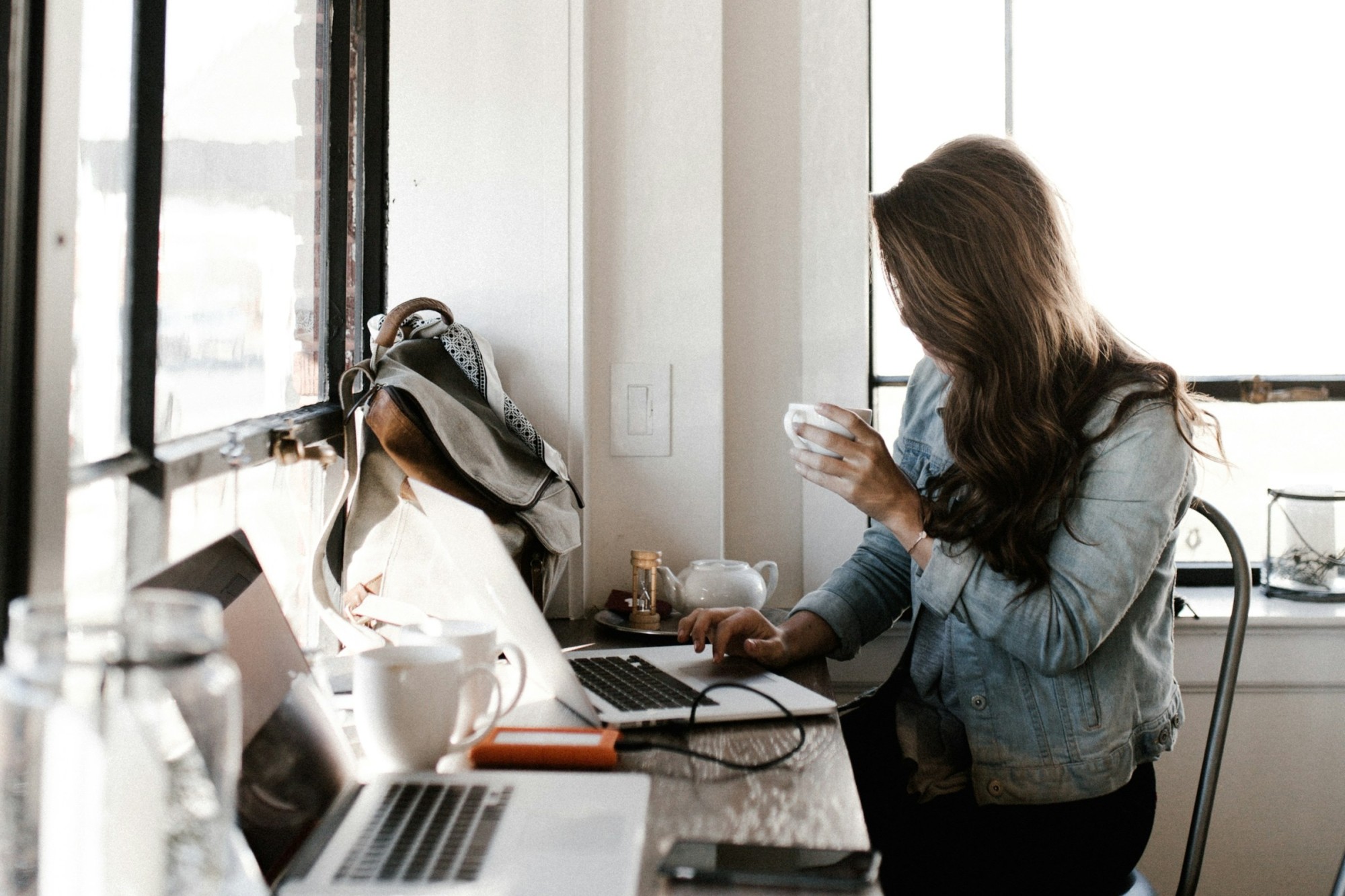 A woman sips an espresso while working on her laptop in a trendy coffee shop