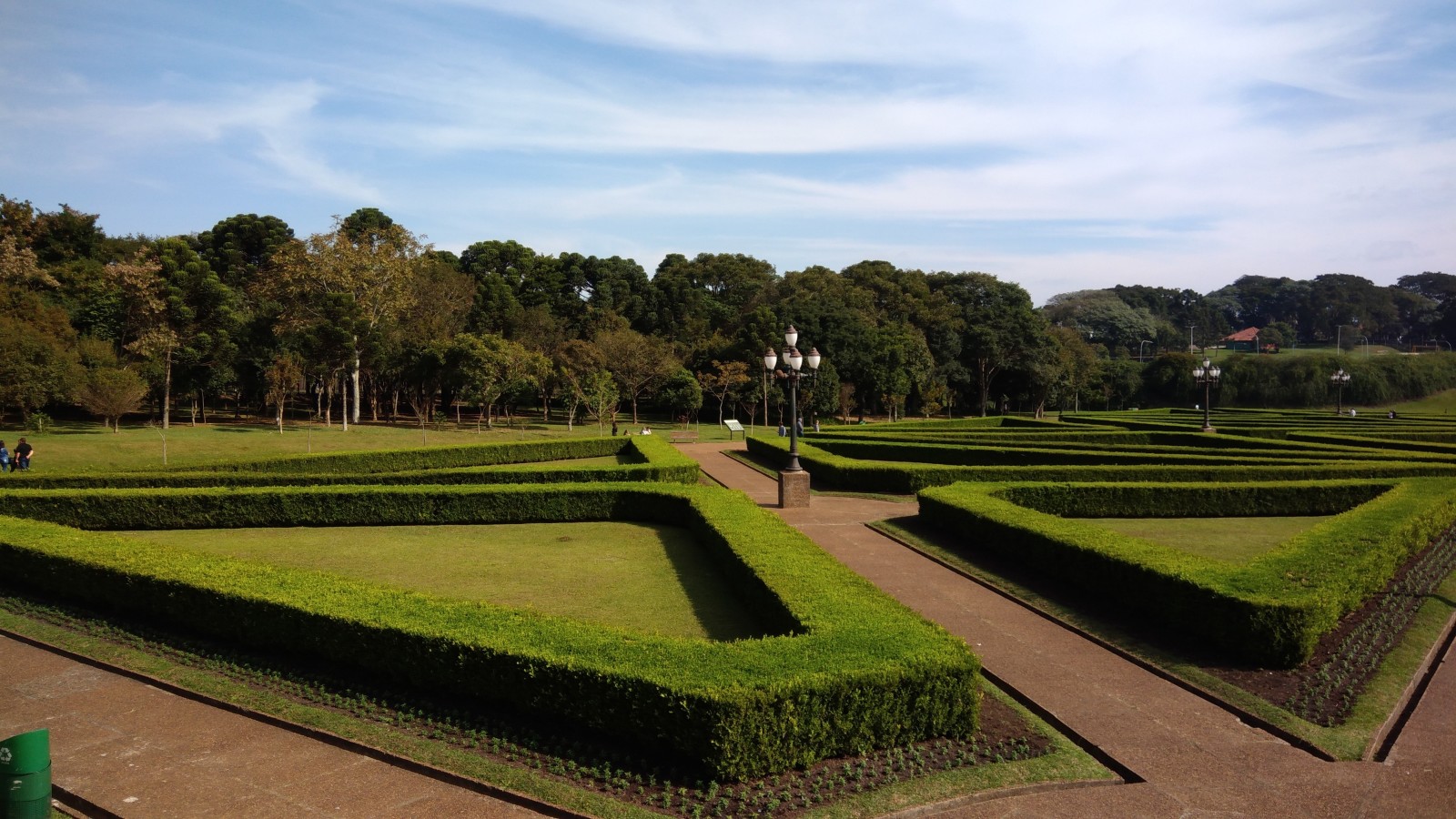 Green trimmed hedges with red brick paths at Jardim Botânico in Brazil.