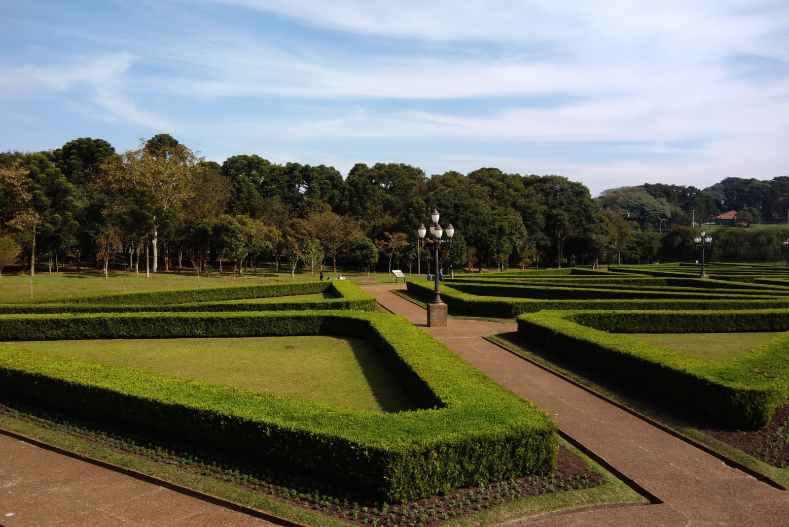 Green trimmed hedges with red brick paths at Jardim Botânico in Brazil.