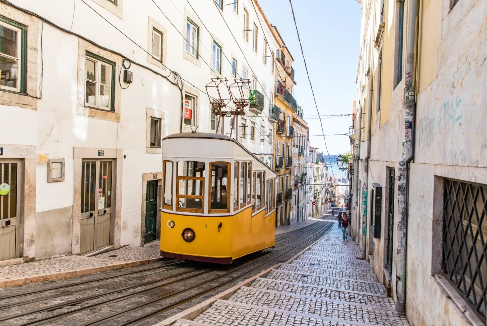 yellow electronic cable car leading up a cobblestoned street