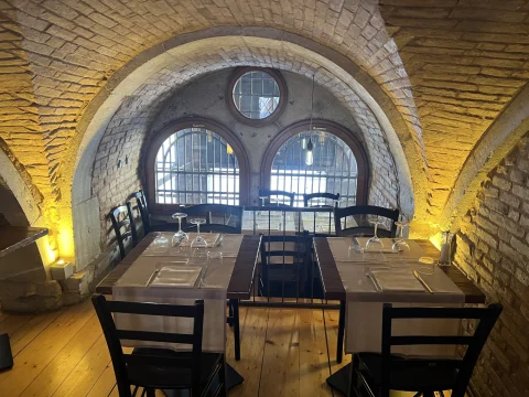 A dining area in a dimly lit room with arched windows