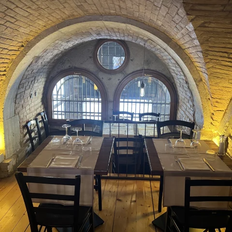 A dining area in a dimly lit room with arched windows