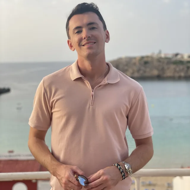 Travel advisor Sam Martin standing on a bridge in a light pink T-Shirt.