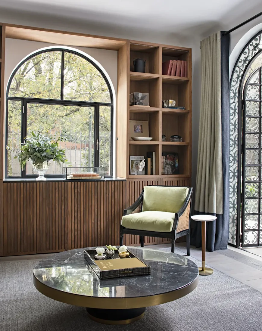a stylish living room with a green L-shaped couch and a circular marble table