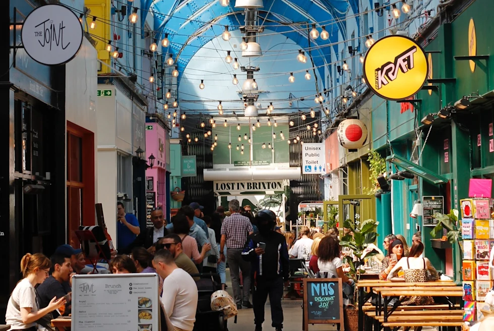 Colorful indoor food market with people sitting.