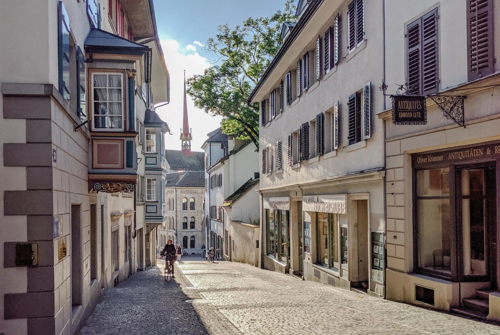 historic neighborhood cobblestone street in a city with a cathedral in the distance 