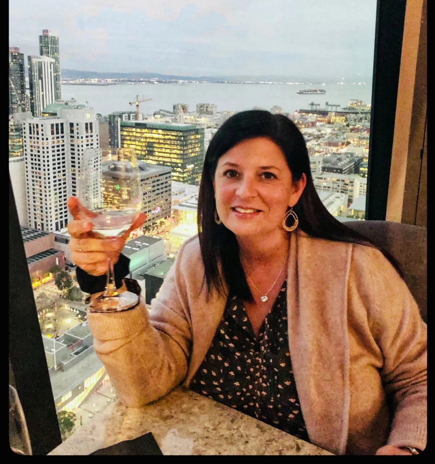 a woman holds a wine glass in a restaurant overlooking a city