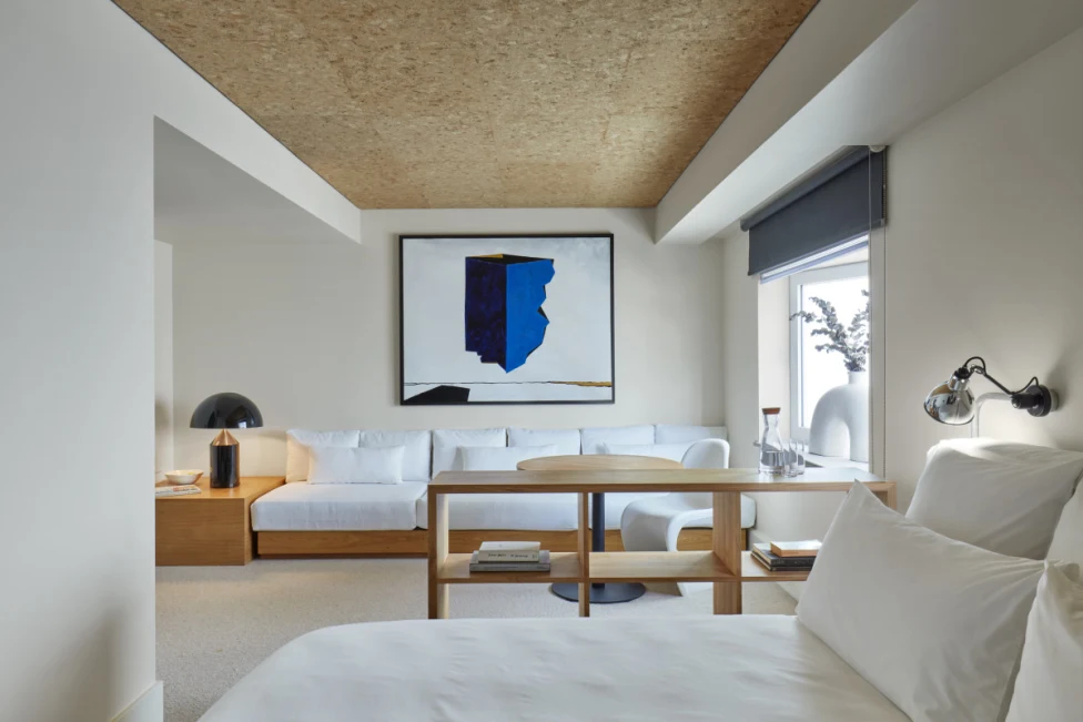 a blue-and-black modern-art painting hangs in a sleek minimalist bedroom