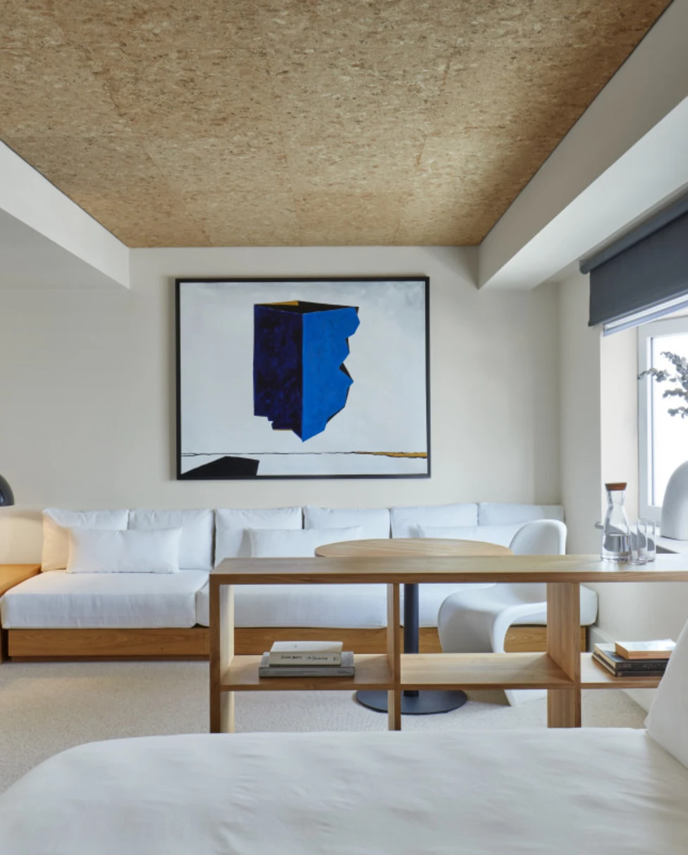 a blue-and-black modern-art painting hangs in a sleek minimalist bedroom