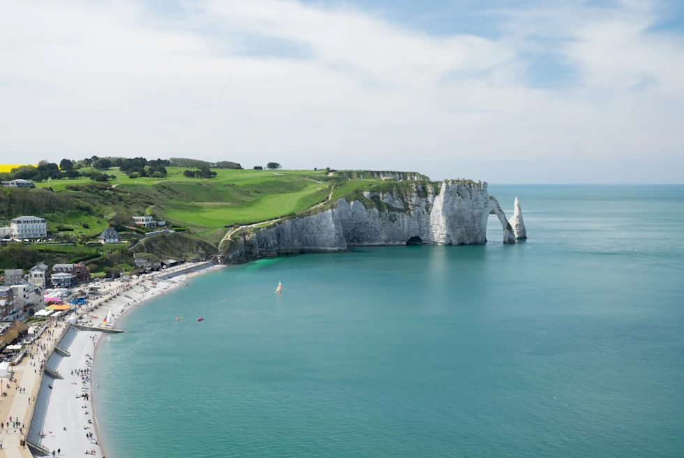 large cliff next to beach and body of water during daytime