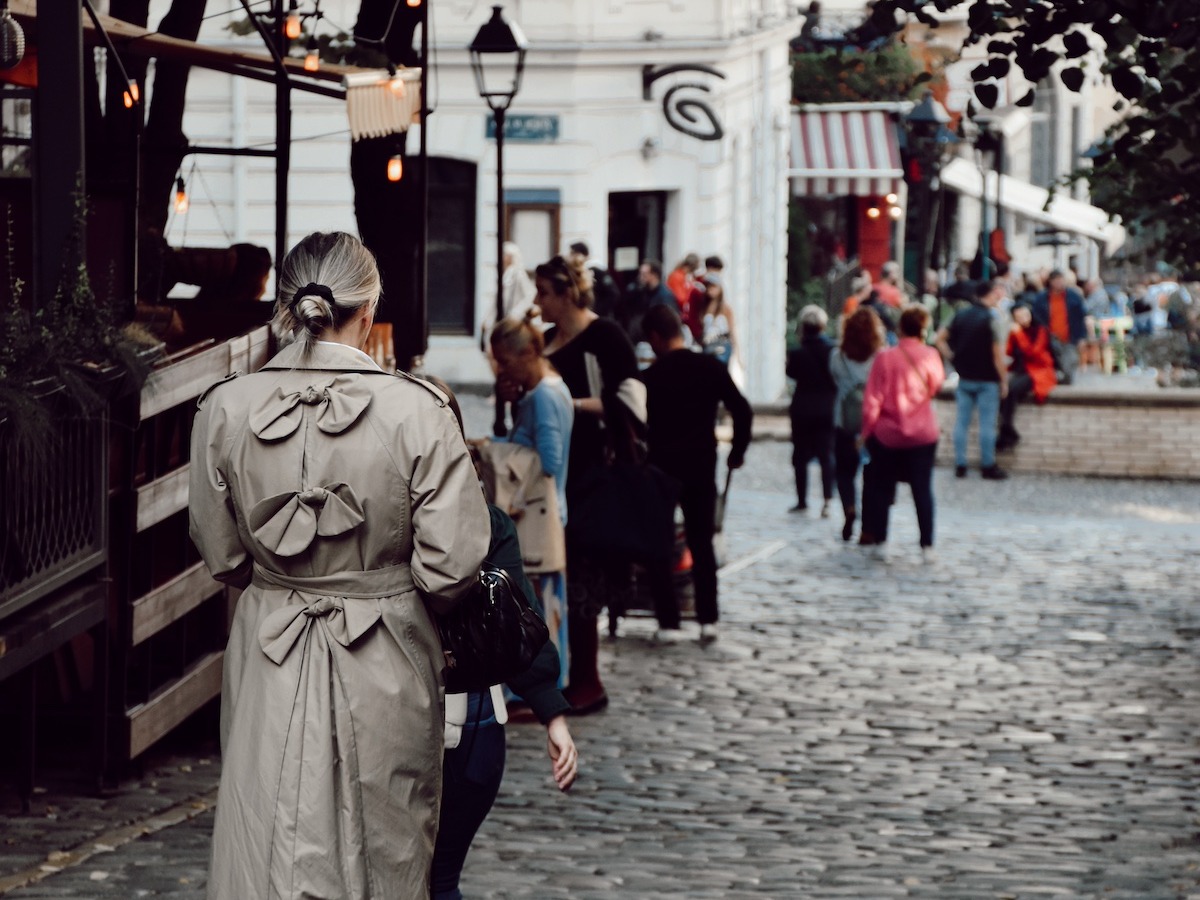 A group of people standing and walking in the street with their back turned toward the camera