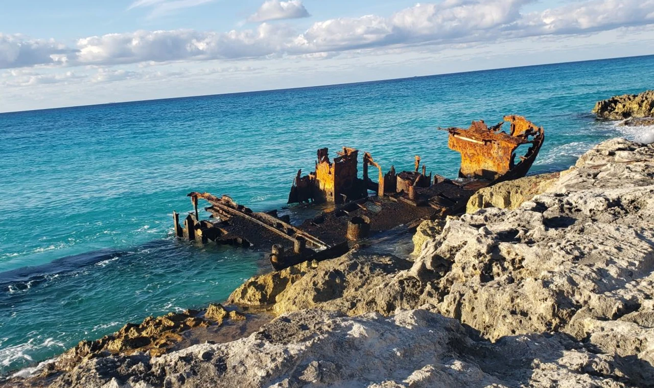 Rusty boat sitting on rocky beach during daytime