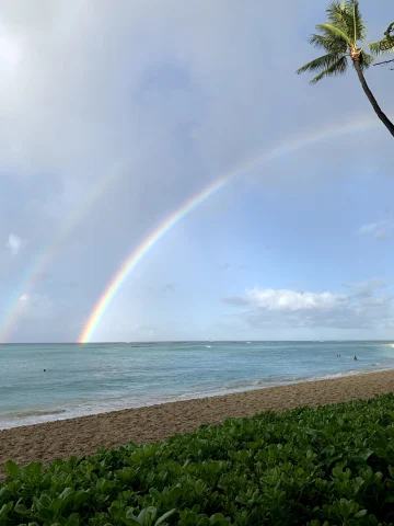 A picture of a beach shore with a rainbow in the sky.
