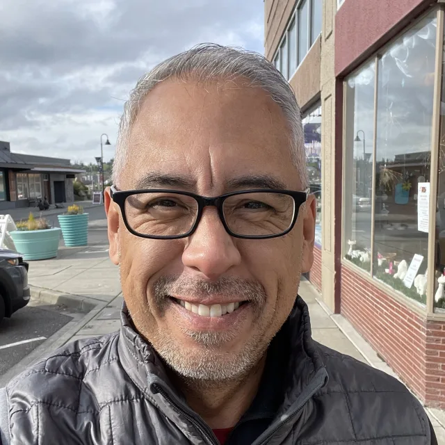 man with silver hair in black-rimmed glasses smiling