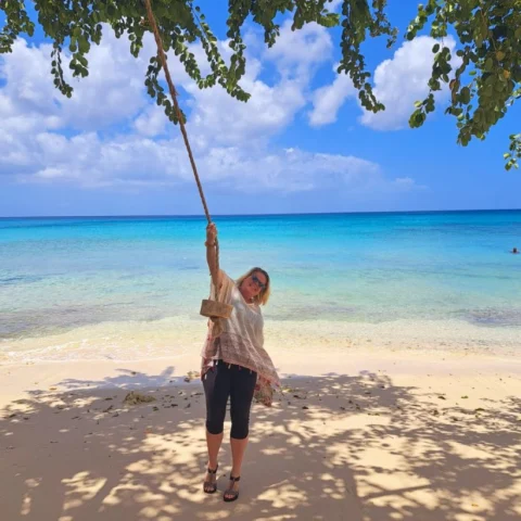 Travel advisor posing on the seaside with a rope swing.