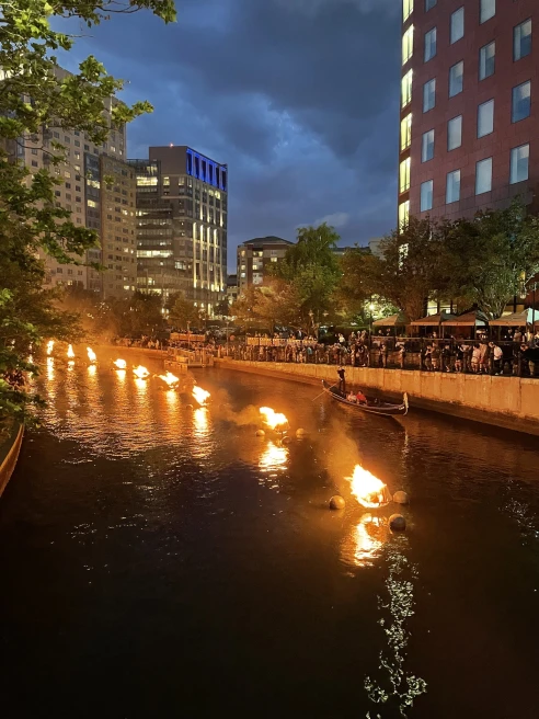 boats with fire show on the river through a city