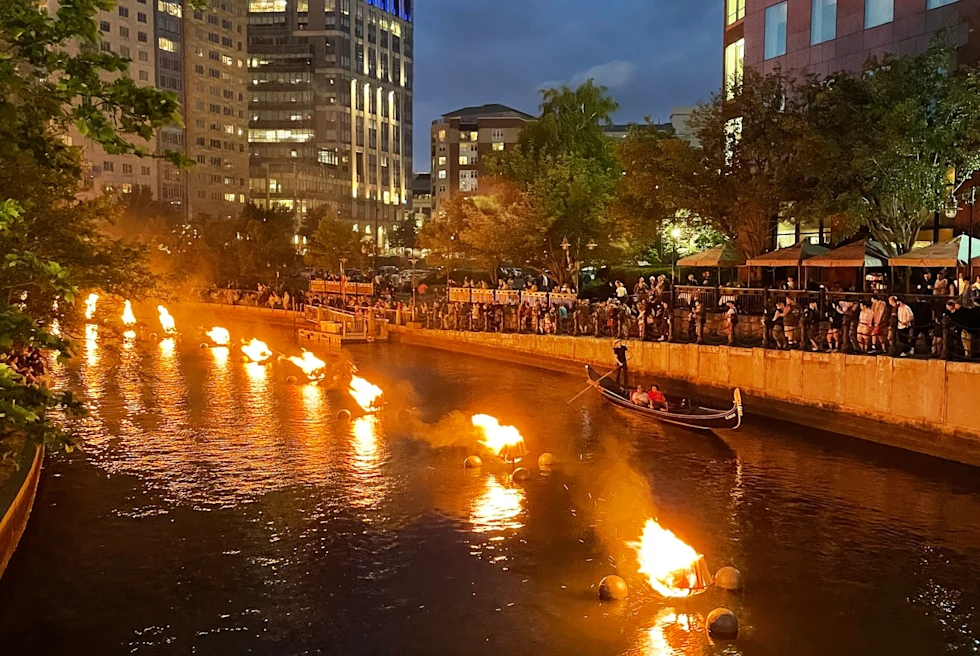 boats with fire show on the river through a city