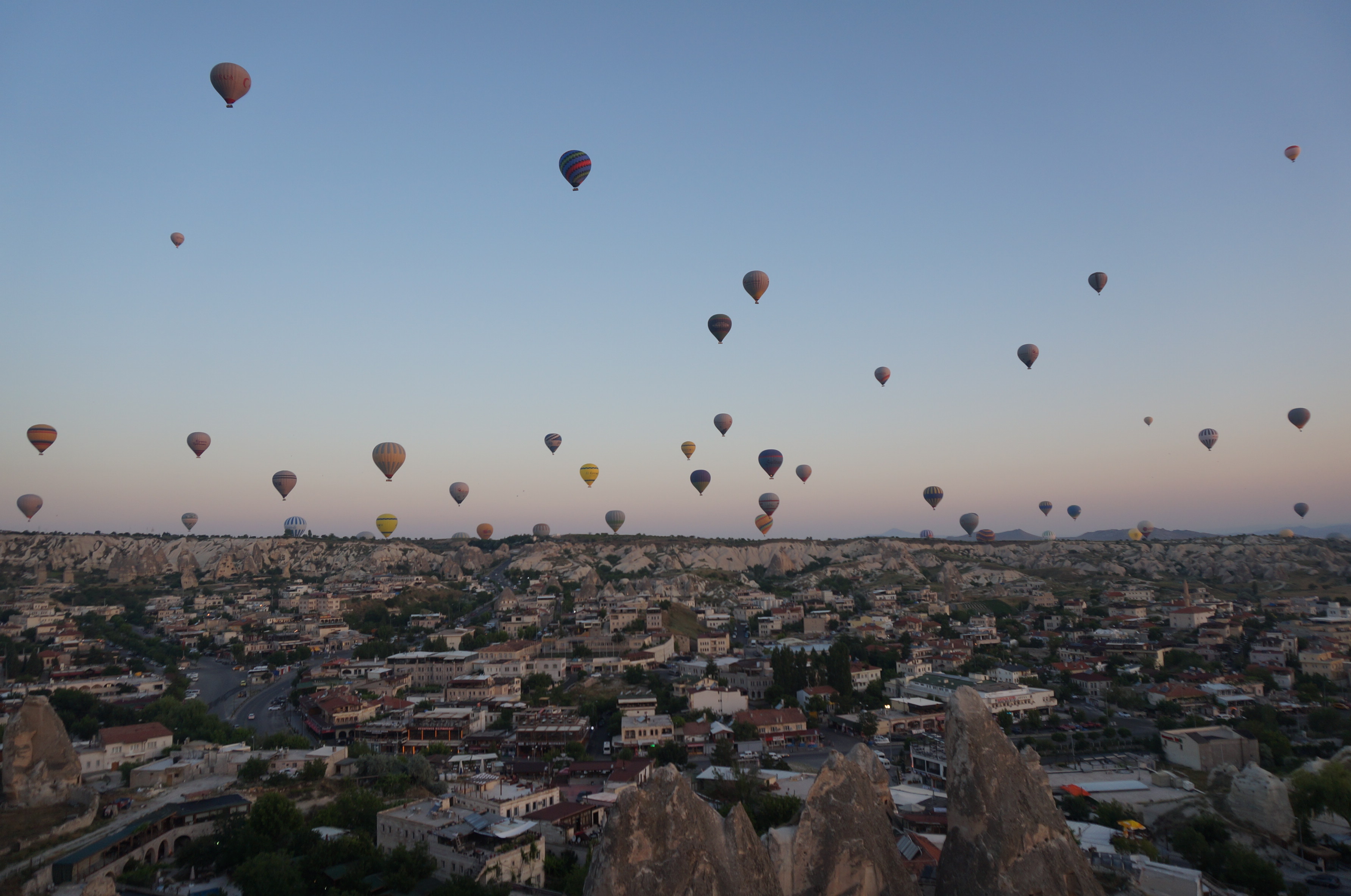 An aerial view of a city with numerous hot air balloons in the sky