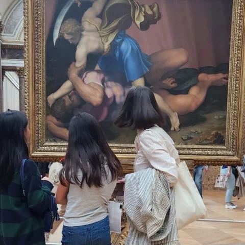 Three women standing in front of a painting. 