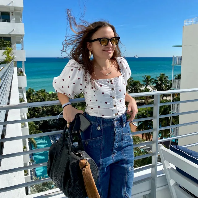 Travel Advisor Hailey Grey Hamilton posing oceanside on a hotel balcony.