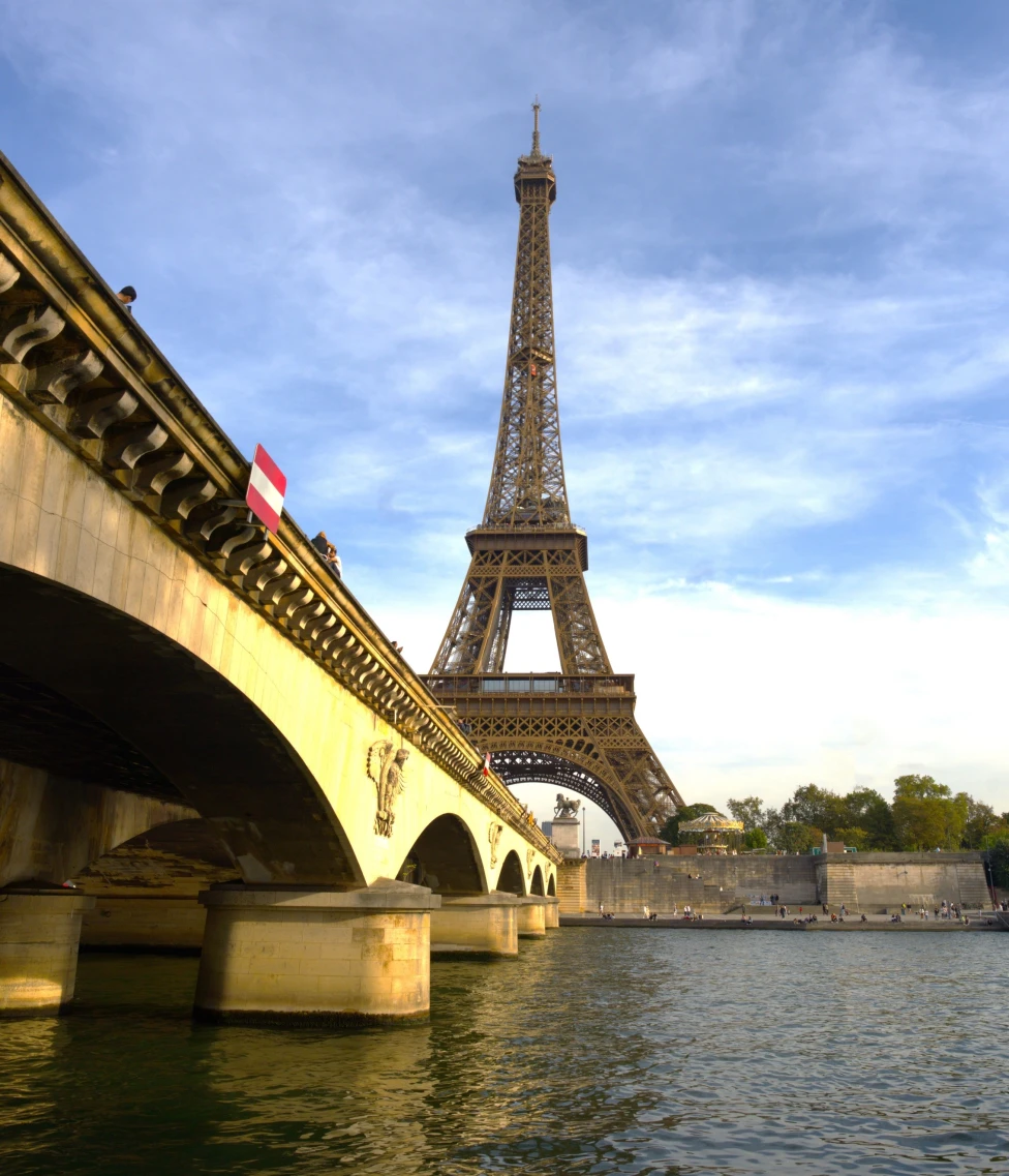 View of the Eiffel Tower with a bridge and body of water in the foreground