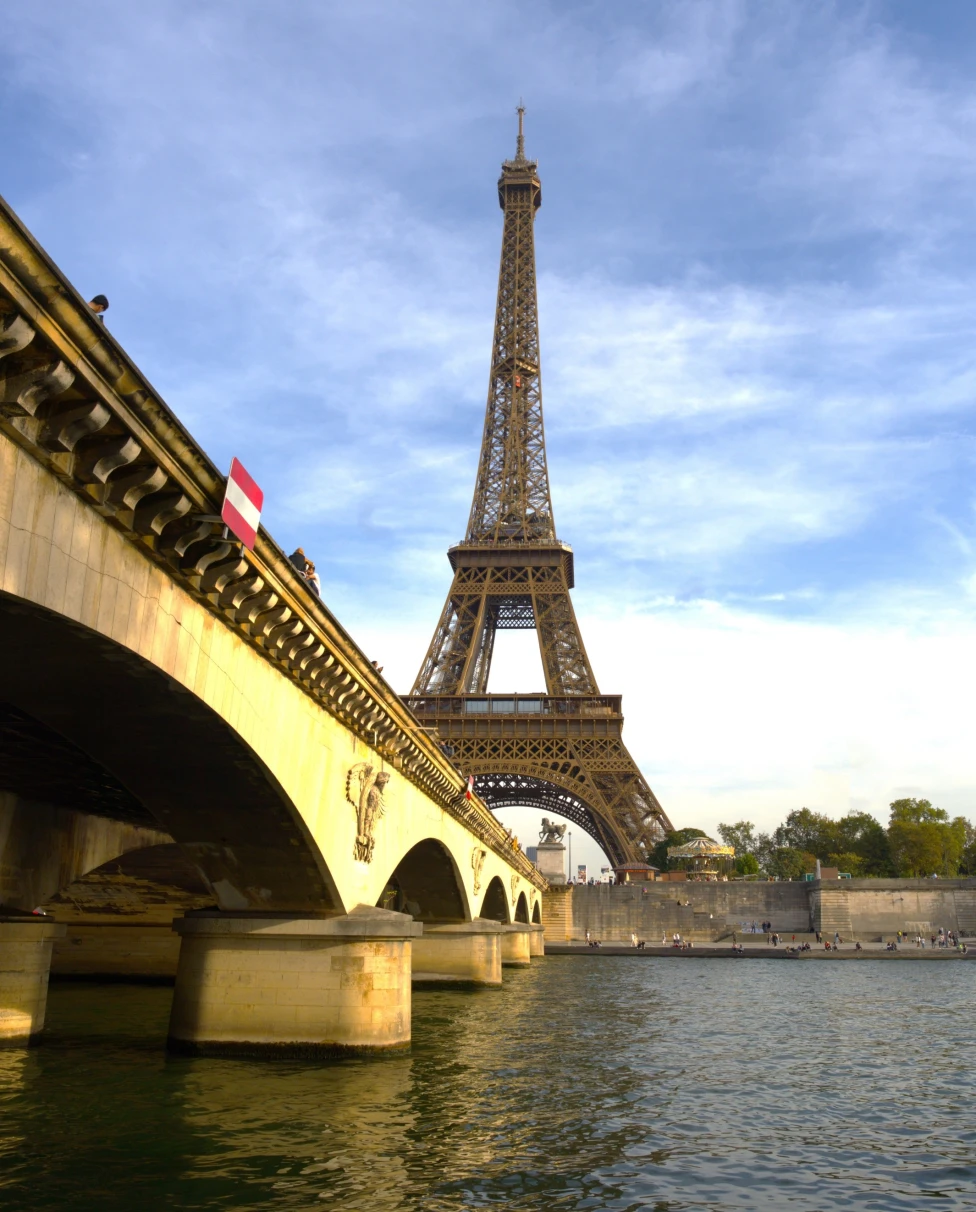 View of the Eiffel Tower with a bridge and body of water in the foreground