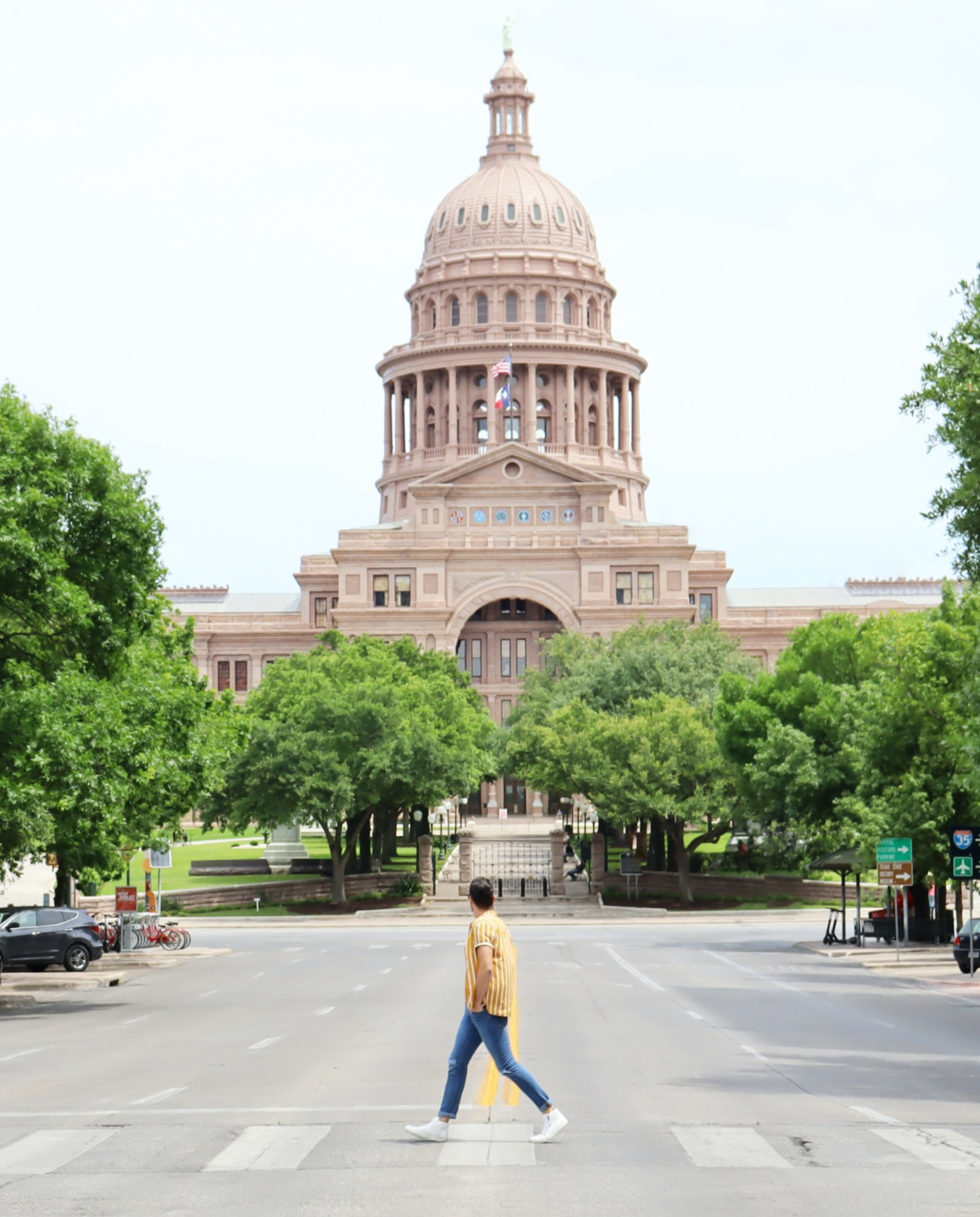 Man walks in crosswalk with capitol building in the back in Austin, Texas
