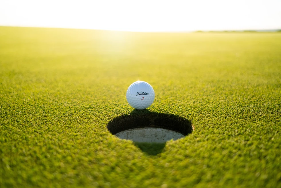 Golf Ball on edge of hole on green golf course