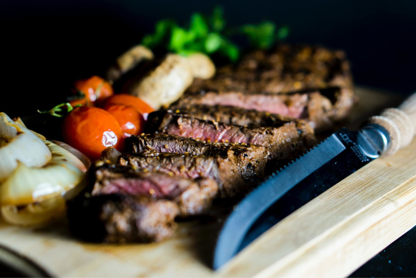 Medium rare steak on cutting board with other ingredients.