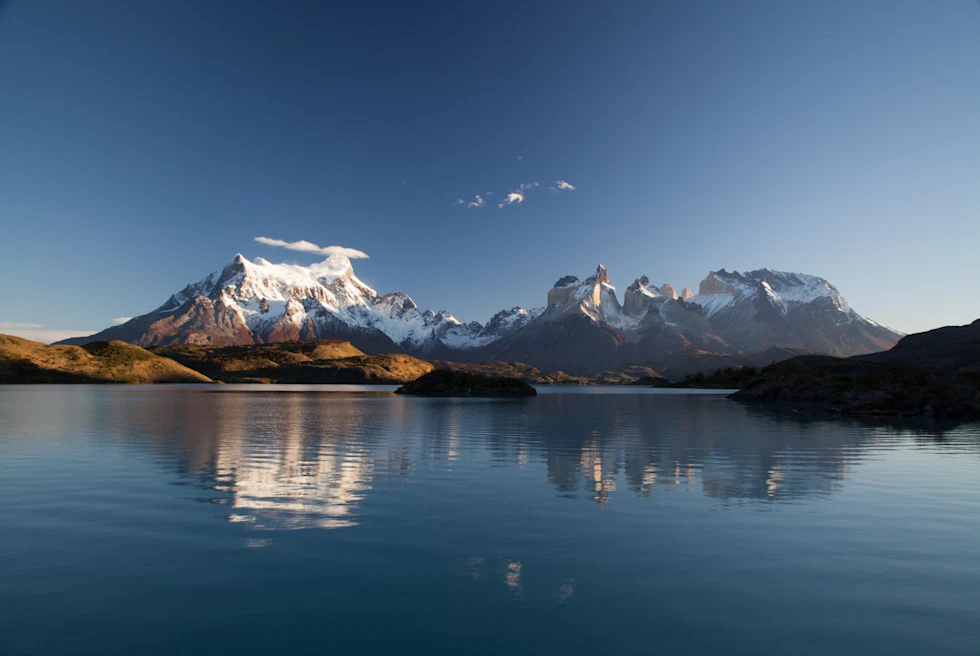 lake next to snow-capped mountains with blue skies