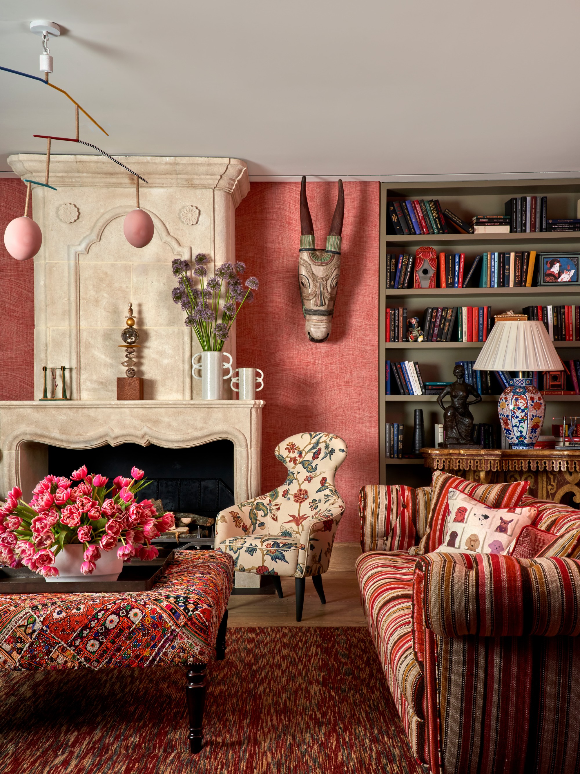 a luxe living room with brightly patterned upholstered furniture, a fireplace, and animal-head sculptures hanging on the wall