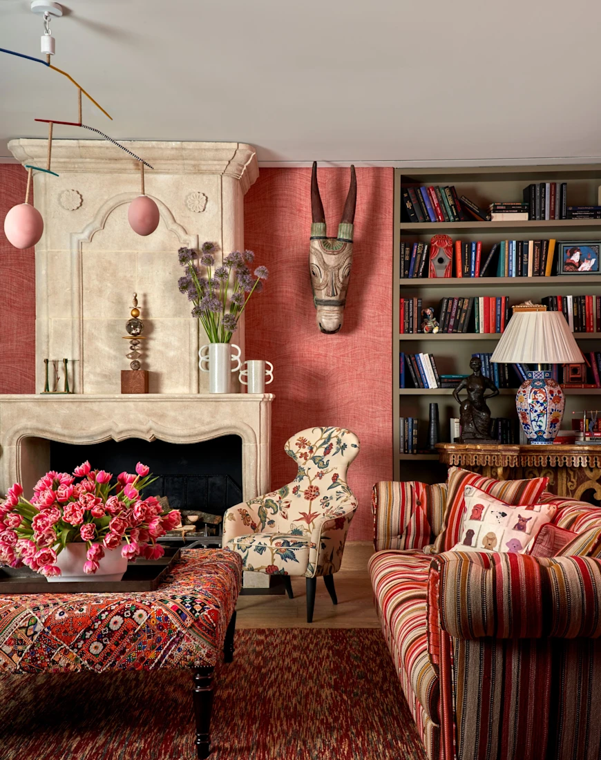 a luxe living room with brightly patterned upholstered furniture, a fireplace, and animal-head sculptures hanging on the wall