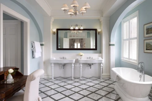 blue-walled bathroom with a white tub and his and hers white sinks
