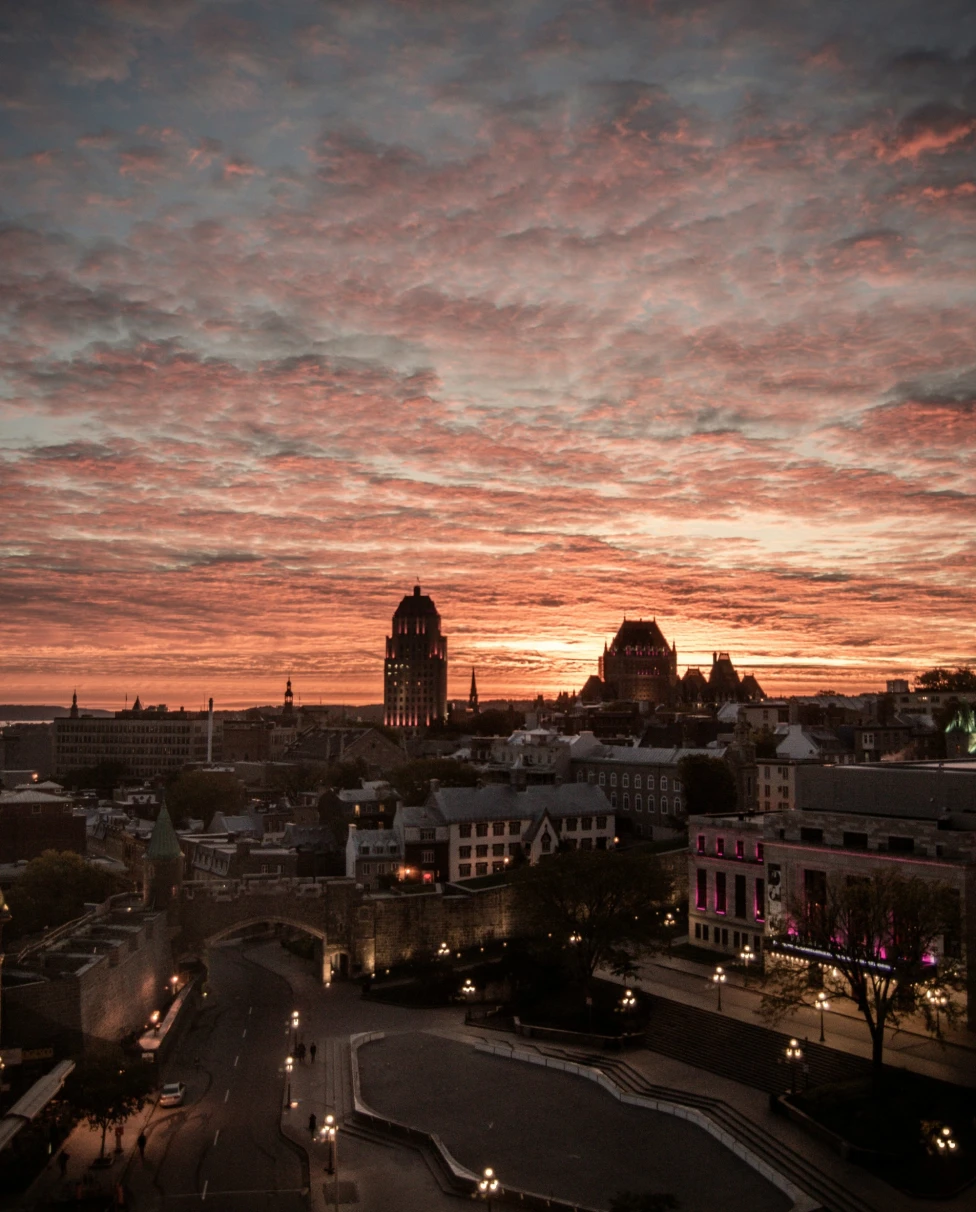 An aerial view of the city buildings under cloudy sky during the sunset.