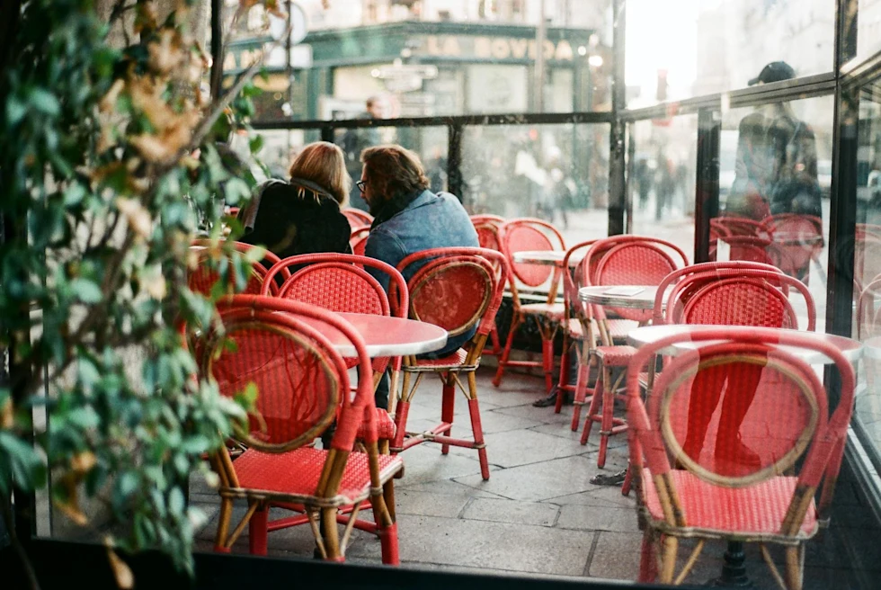 Inside of a restaurant with red chairs and tables.