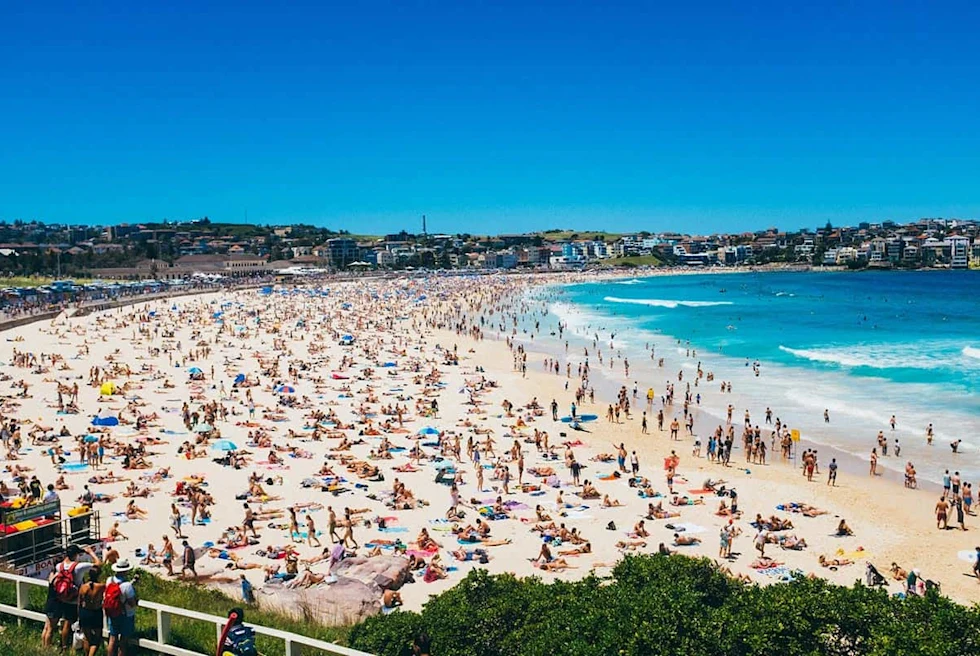 People enjoying on a beach with clear blue water and white sand.