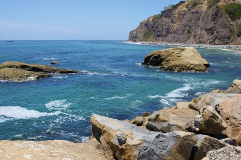 Blue ocean with cliffs and green rocks in Dana point California