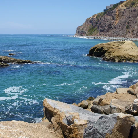 Blue ocean with cliffs and green rocks in Dana point California