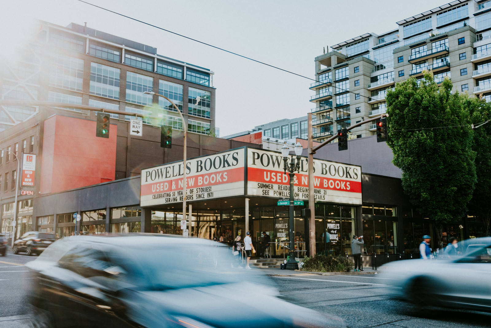 A red and white Powell's Books sign over a storefront in Portland, Oregon with cars passing by.