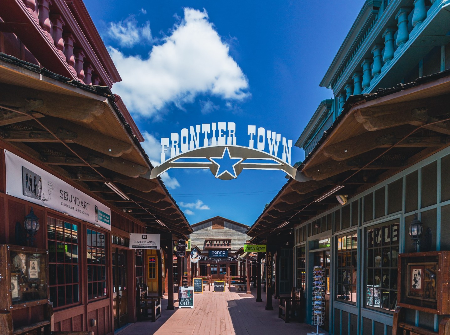 Storefronts with frontier town sign hanging on a sunny day