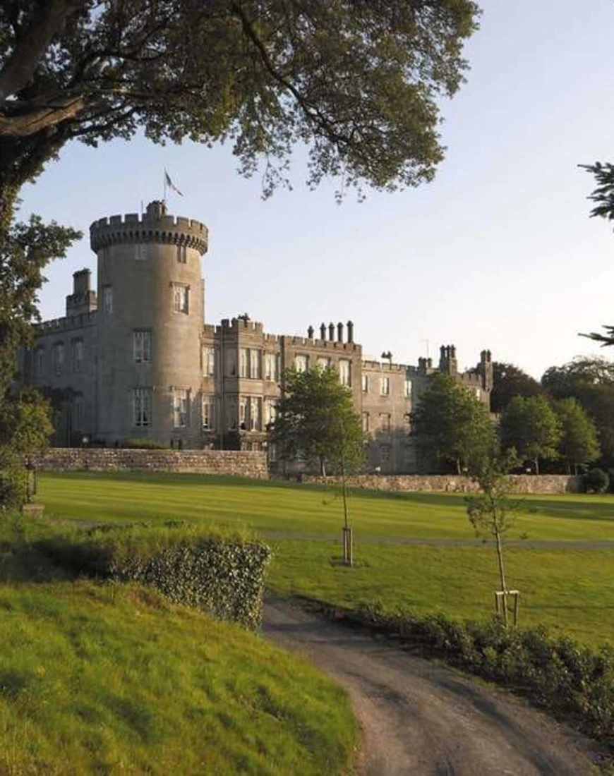 a gray stone castle amid a sprawling green slice of land