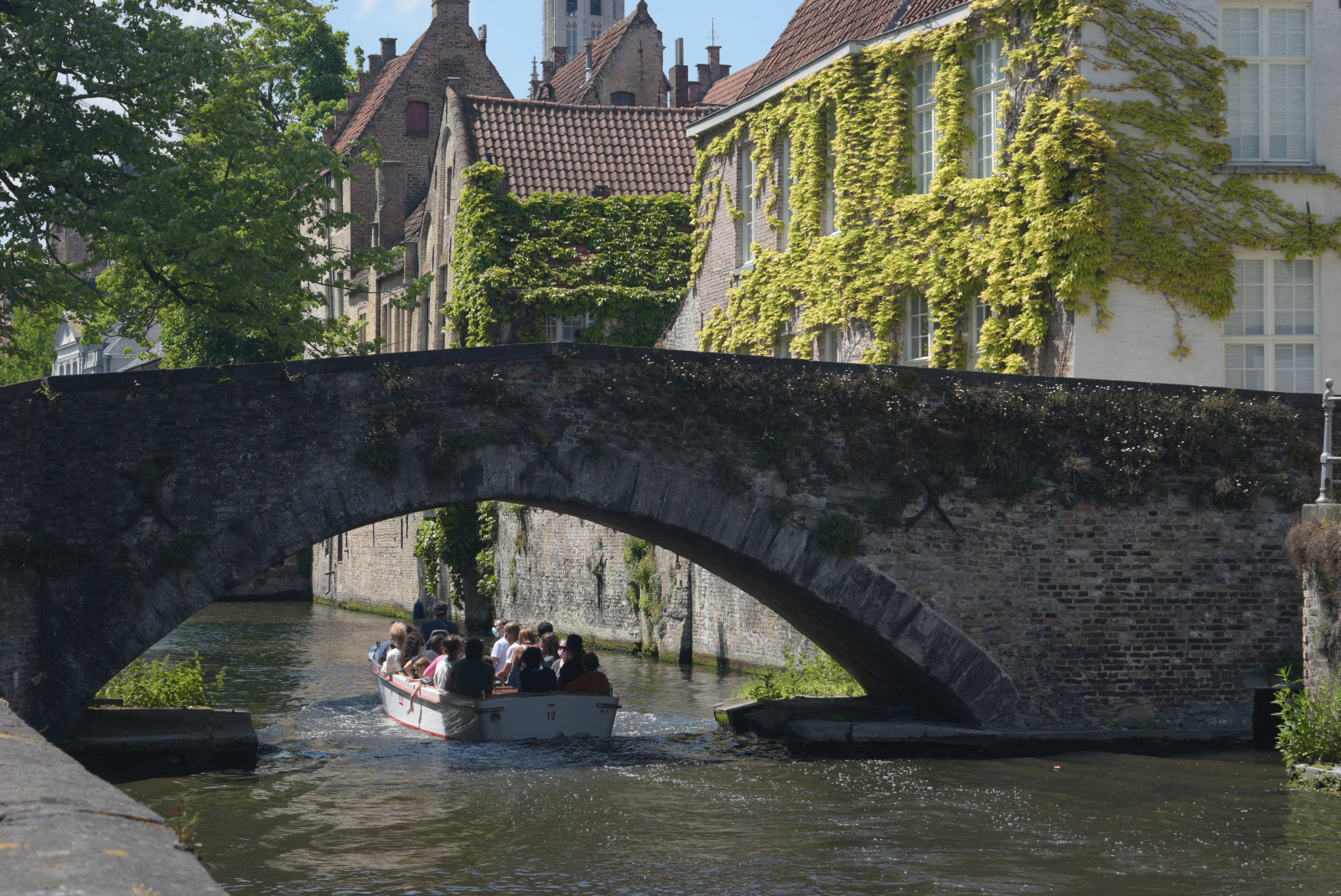 boat under bridge next to building during daytime