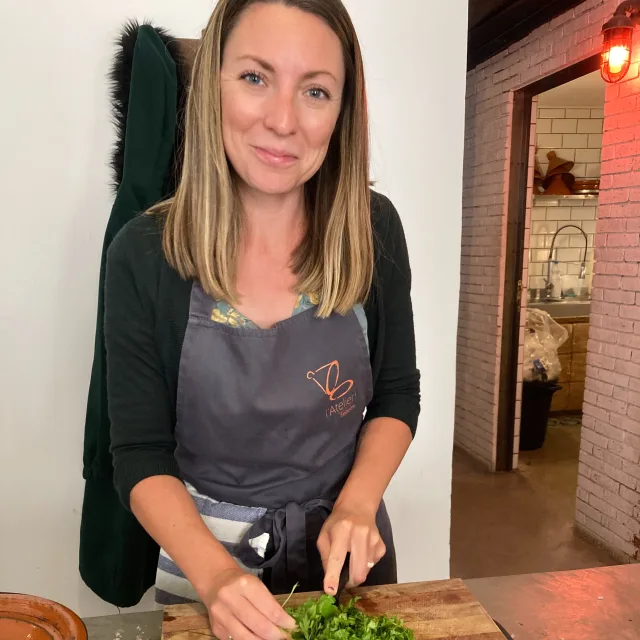 Travel Advisor Leandra Beabout with a gray apron chopping green veggies.