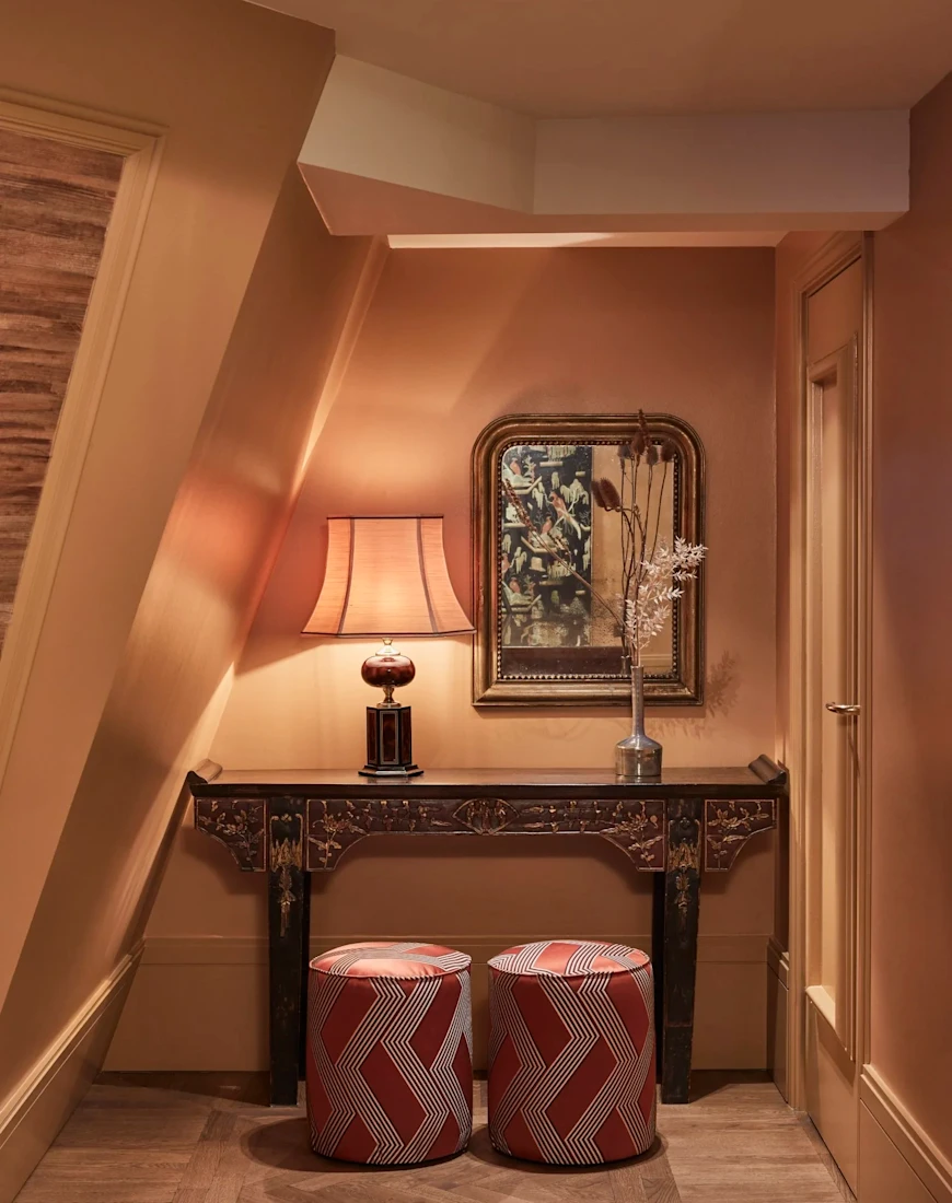 two cylindrical stools in front of a table in a hallway
