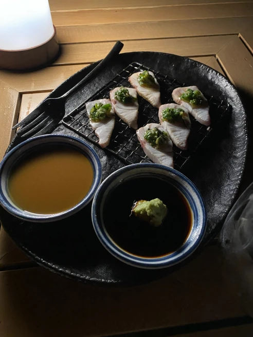 plate filled with sashimi, accompanied by two bowls of sauce
