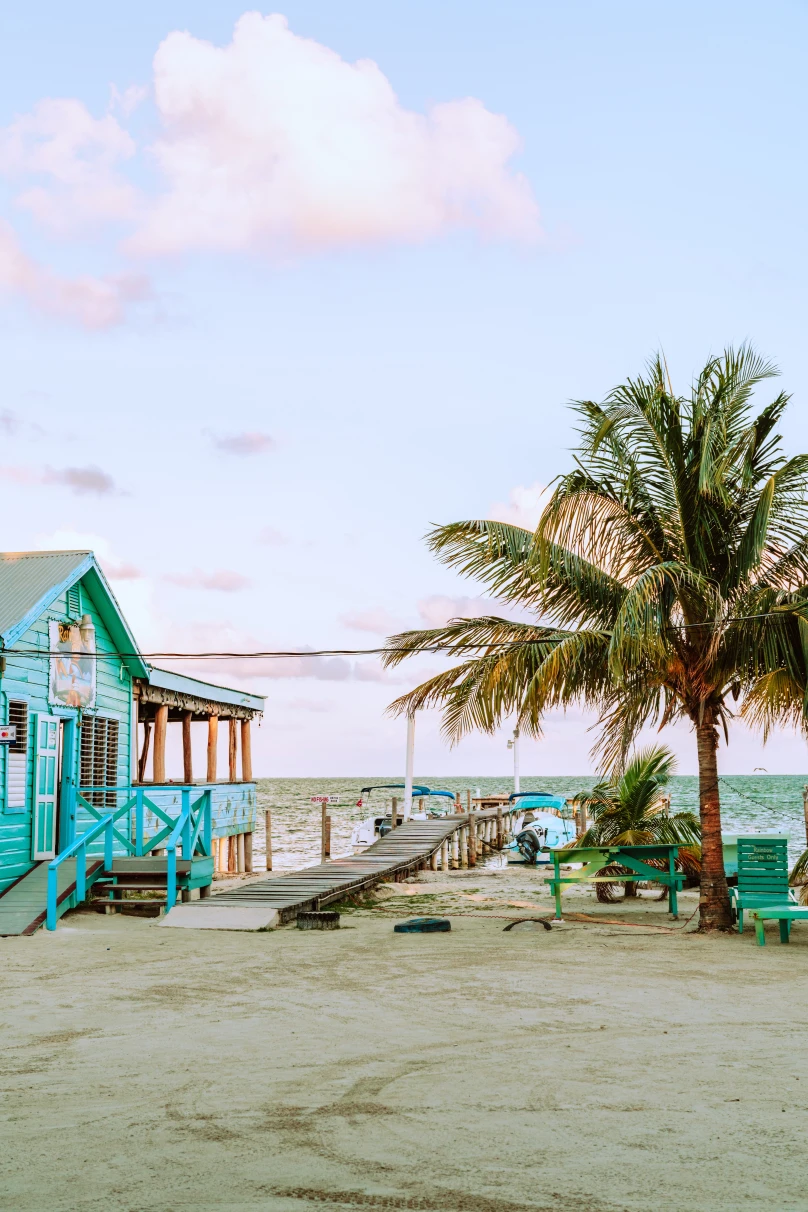 a staple of any belize itinerary: beautiful beach with palm trees next to a colorful building