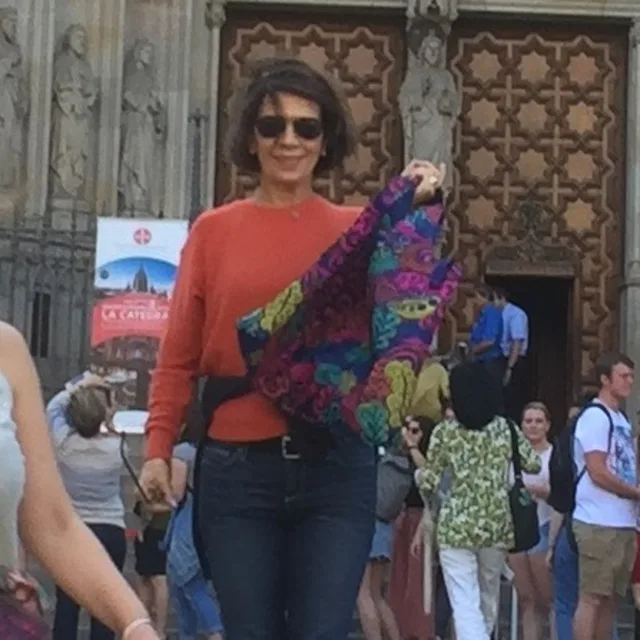 Travel advisor Cheryl Ann Murphy with a colorful bag wearing a red shirt.