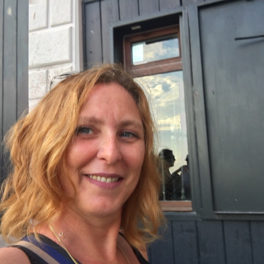 Fora travel agent Teresa Pappalardo smiles with black building and window in background